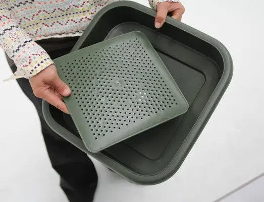 A person holds a Hungry Bin Replacement Filter—a green square container with a perforated insert and solid lid, perfect for draining, steaming food, or filtering liquid fertilizer.